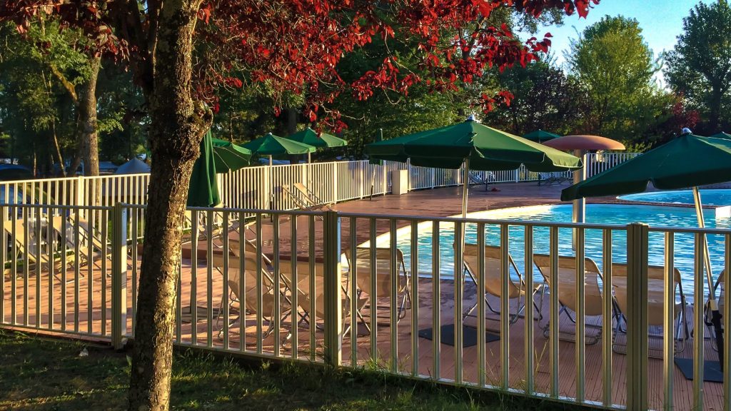 Fenced in pool with deck chairs and umbrellas
