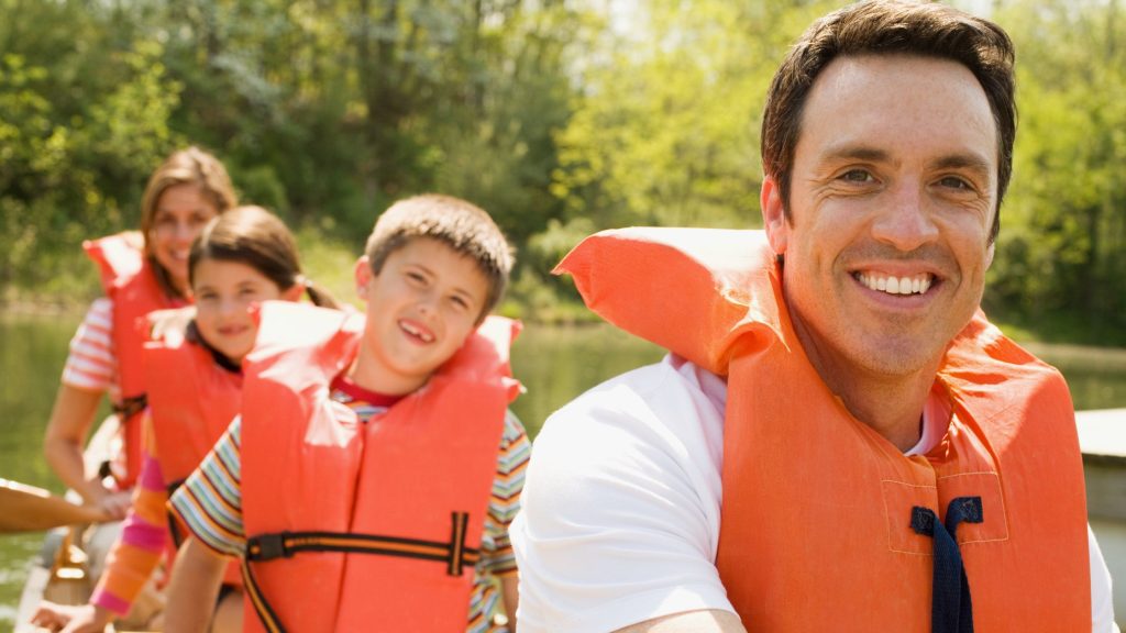 Family canoeing with orange life vests on