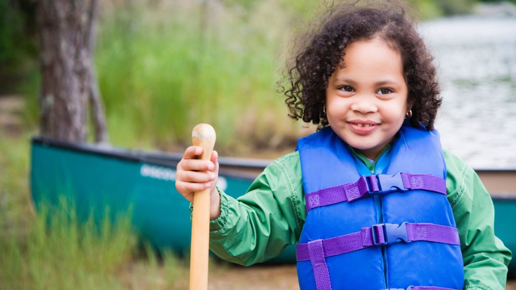 Young girl with a canoe paddle and a blue lifejacket