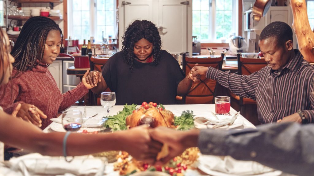Family united in prayer around Thanksgiving meal