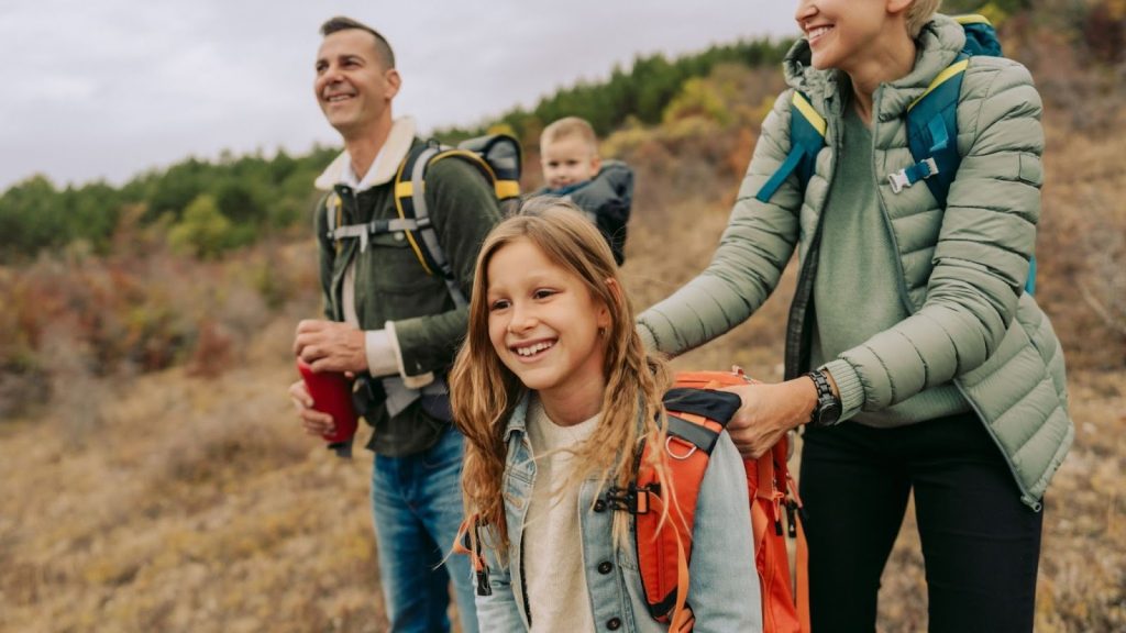 Family of four going on a hike. Mom, dad, daughter and baby son in a carrier.